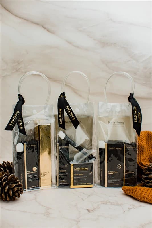 Drei Karin Herzog Geschenktaschen mit schwarzen Bändern auf Marmor